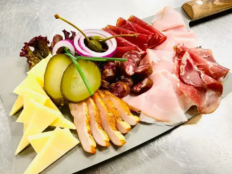 Platte mit Rohschinken, Trockenfleisch, Salami, Käseecken, Essiggurken, Zwiebelringen und Salat