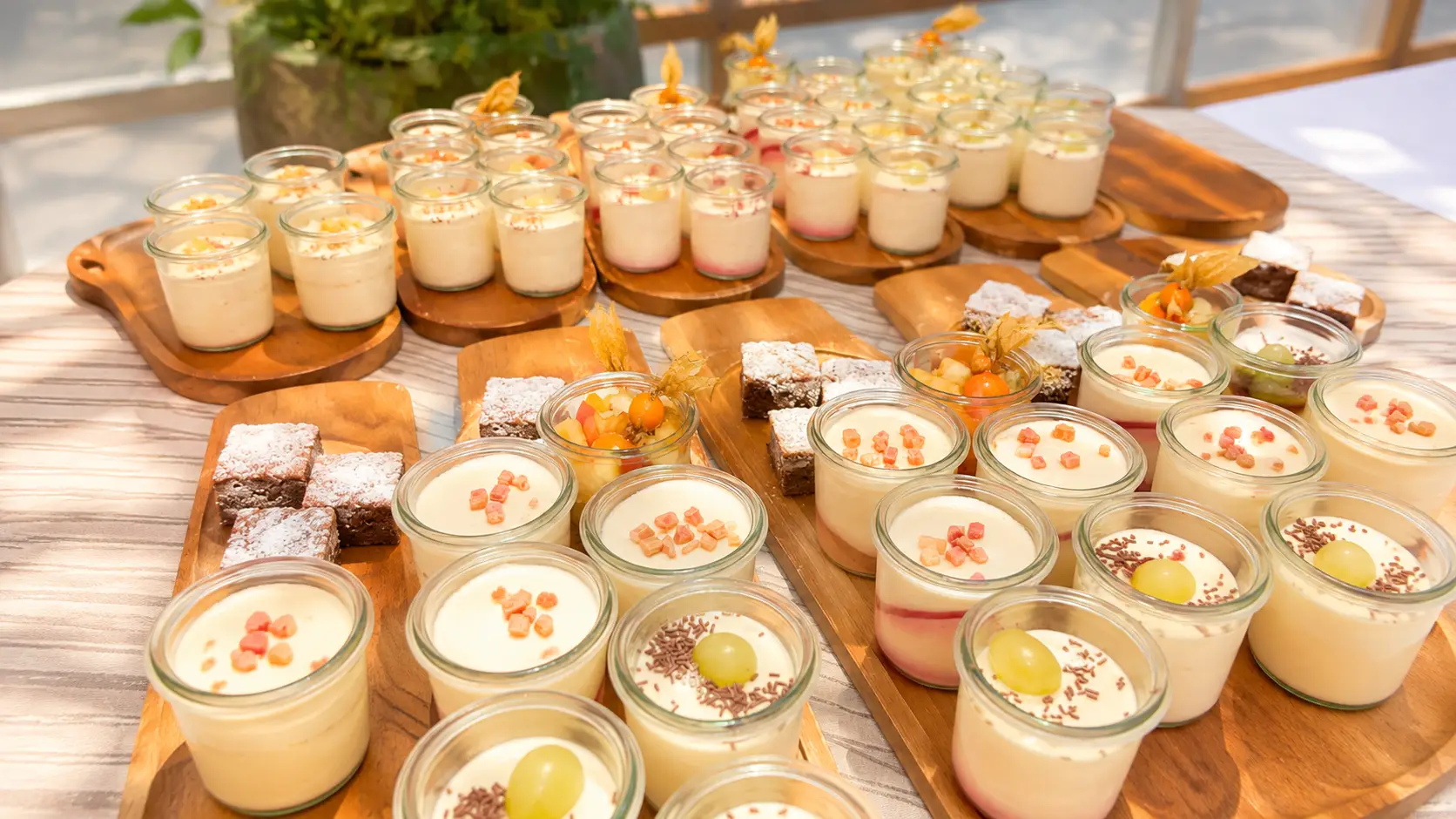 Holzbretter mit vielen Dessertgläschen, Cremes, Fruchtsalat, Physalis und Brownie-Würfeln